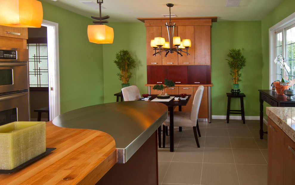 This is an example of a mid-sized asian u-shaped eat-in kitchen in Orange County with a single-bowl sink, flat-panel cabinets, medium wood cabinets, stainless steel benchtops, green splashback, glass tile splashback, stainless steel appliances, porcelain floors and multiple islands.