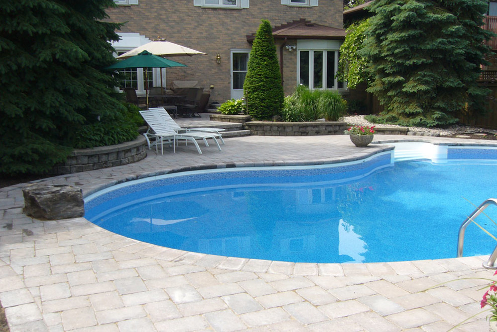 Example of a mid-sized backyard concrete paver and freeform pool design in Toronto
