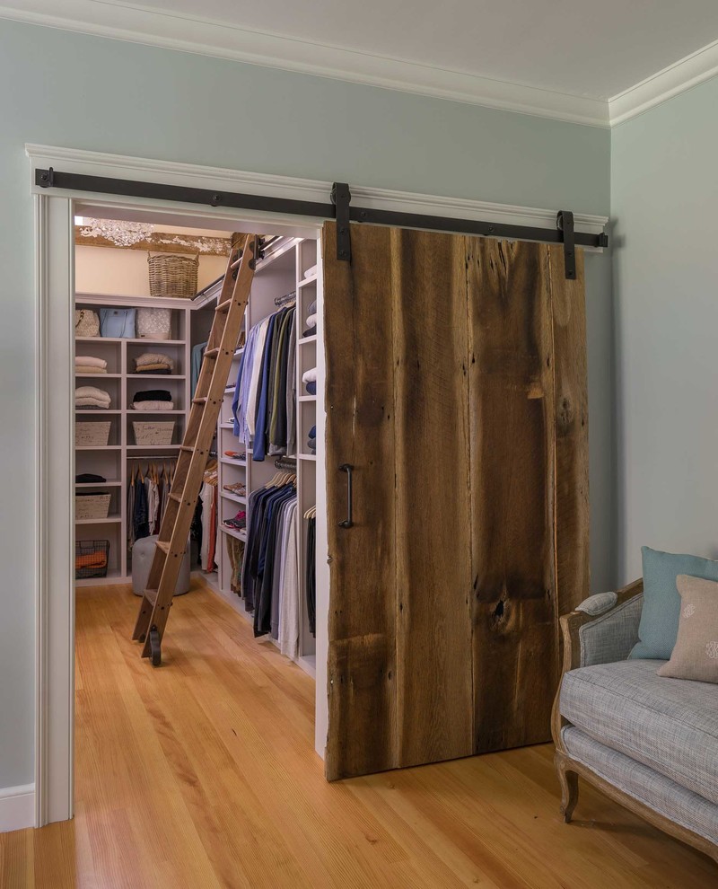 Inspiration for a mid-sized country walk-in wardrobe in Boston with open cabinets, white cabinets and medium hardwood floors.