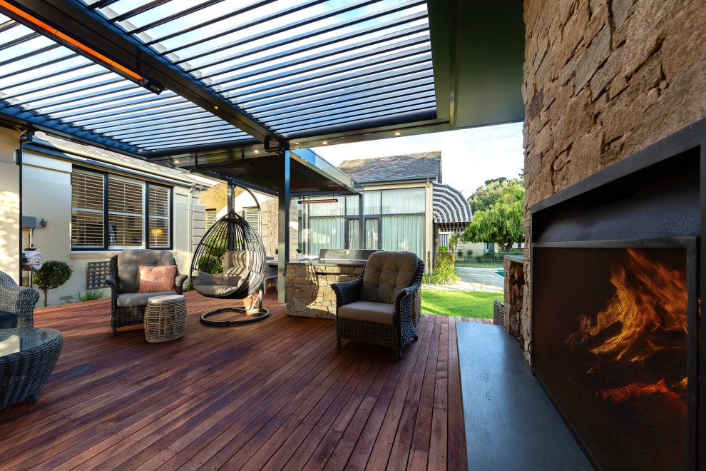 Inspiration pour un grand porche d'entrée de maison arrière design avec une cheminée, une terrasse en bois et une pergola.
