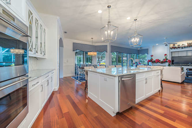 Photo of a mid-sized transitional l-shaped eat-in kitchen in Miami with shaker cabinets, white cabinets, granite benchtops, multi-coloured splashback, marble splashback, stainless steel appliances, medium hardwood floors, with island and an undermount sink.