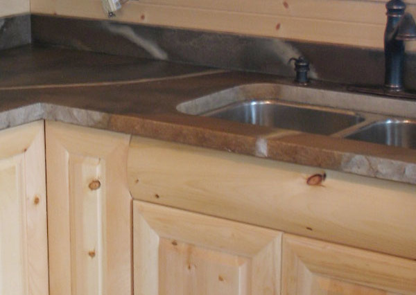 Example of a medium tone wood floor kitchen design with light wood cabinets, concrete countertops and stainless steel appliances