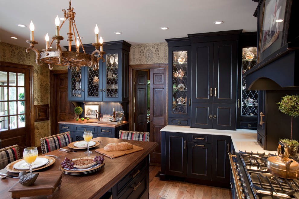 Photo of a large traditional u-shaped eat-in kitchen in New York with recessed-panel cabinets, black cabinets, wood benchtops, medium hardwood floors, with island, beige splashback and black appliances.