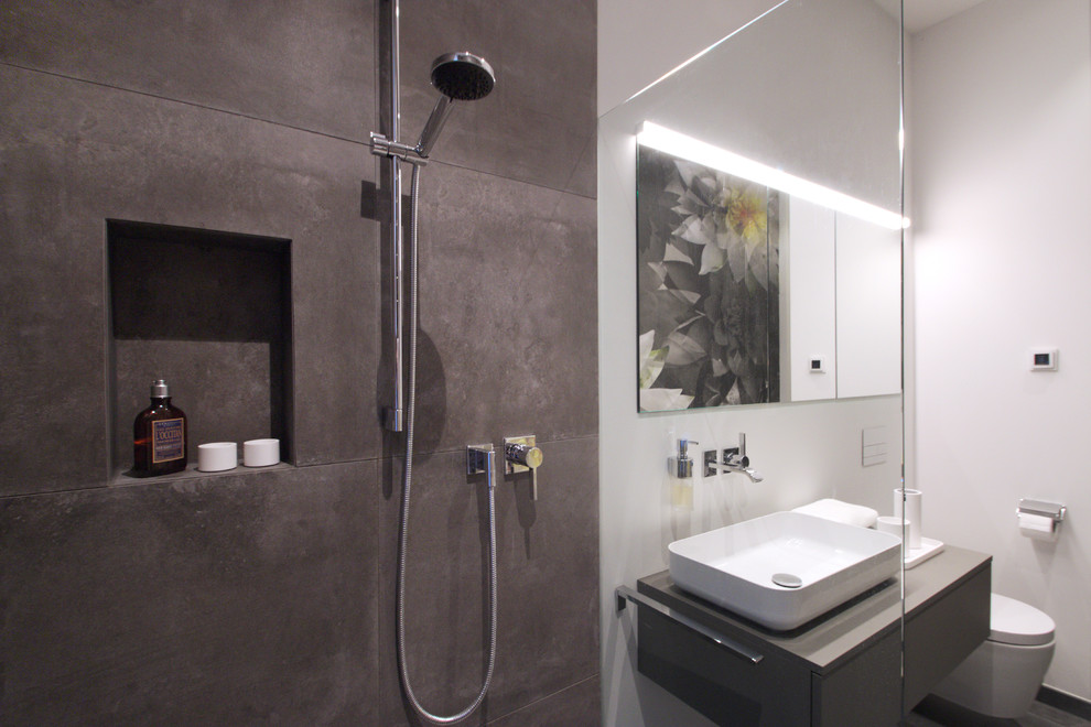 Kleines Modernes Duschbad mit flächenbündigen Schrankfronten, grauen Schränken, offener Dusche, Wandtoilette, grauen Fliesen, weißer Wandfarbe, Aufsatzwaschbecken, grauem Boden, offener Dusche und grauer Waschtischplatte in Berlin