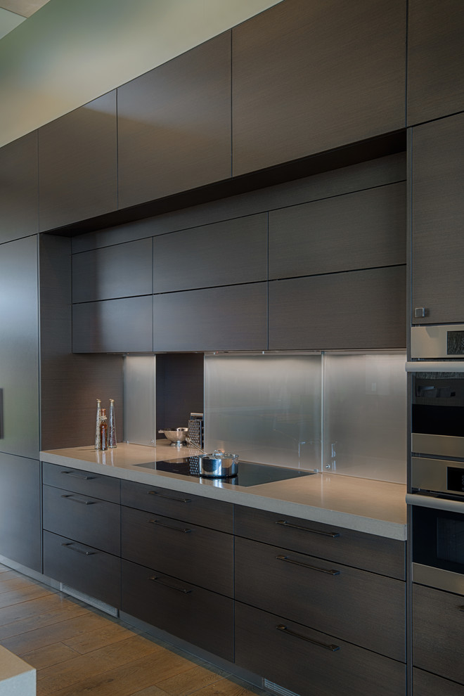 This is an example of a mid-sized contemporary l-shaped eat-in kitchen in San Francisco with an undermount sink, flat-panel cabinets, dark wood cabinets, stainless steel appliances, with island, quartz benchtops, grey splashback, glass tile splashback and medium hardwood floors.