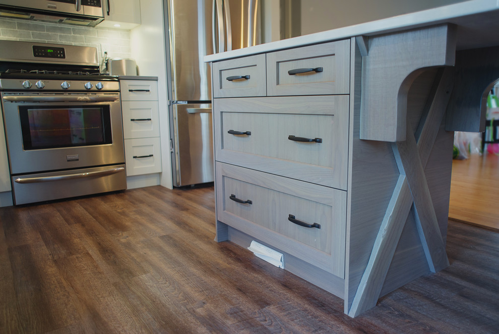 Example of a mid-sized transitional l-shaped open concept kitchen design in Vancouver with shaker cabinets, white cabinets, quartz countertops, gray backsplash, stainless steel appliances and an island