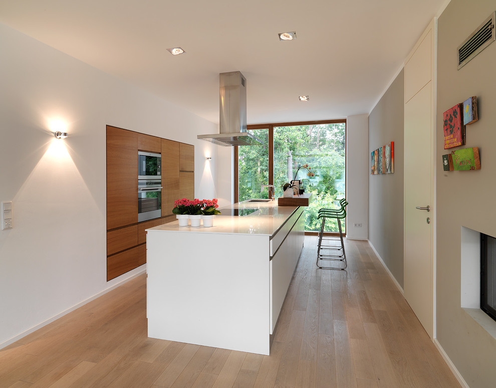 Mid-sized contemporary separate kitchen in Nuremberg with flat-panel cabinets, medium wood cabinets, medium hardwood floors, with island, an undermount sink and panelled appliances.
