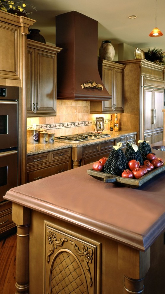 Inspiration for a large mediterranean u-shaped medium tone wood floor eat-in kitchen remodel in Phoenix with an undermount sink, beaded inset cabinets, light wood cabinets, wood countertops, pink backsplash, stone tile backsplash, stainless steel appliances and an island