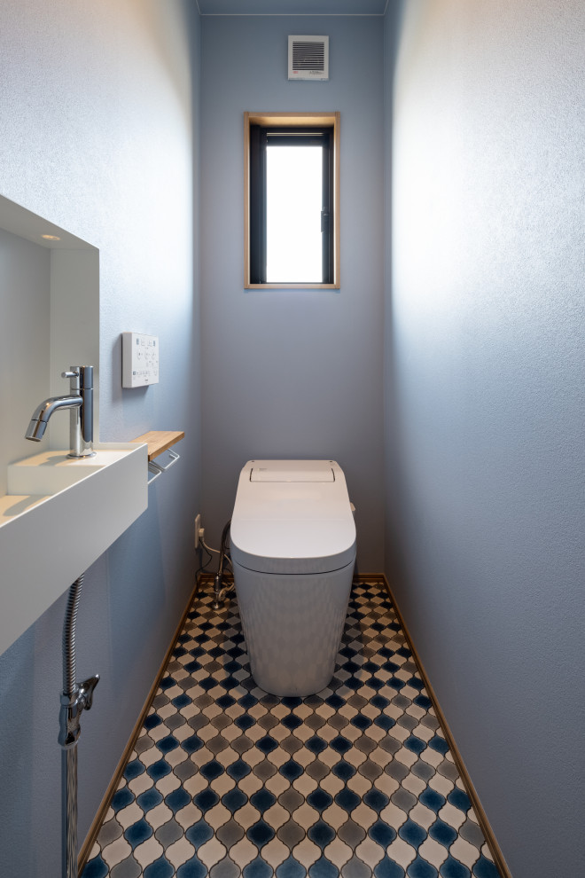 Идея дизайна: маленький туалет в стиле модернизм с унитазом-моноблоком, синими стенами, полом из винила, разноцветным полом, потолком с обоями и обоями на стенах для на участке и в саду