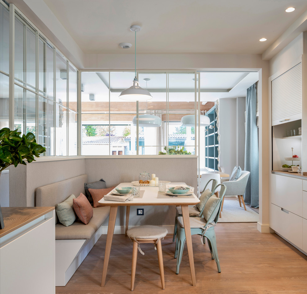 This is an example of an expansive scandinavian kitchen/dining combo in Bilbao with laminate floors, brown floor and white walls.