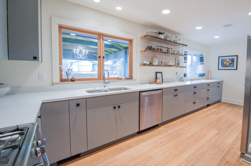 Mid-sized midcentury u-shaped kitchen in Portland with an undermount sink, flat-panel cabinets, grey cabinets, concrete benchtops, white splashback, cement tile splashback, stainless steel appliances and bamboo floors.