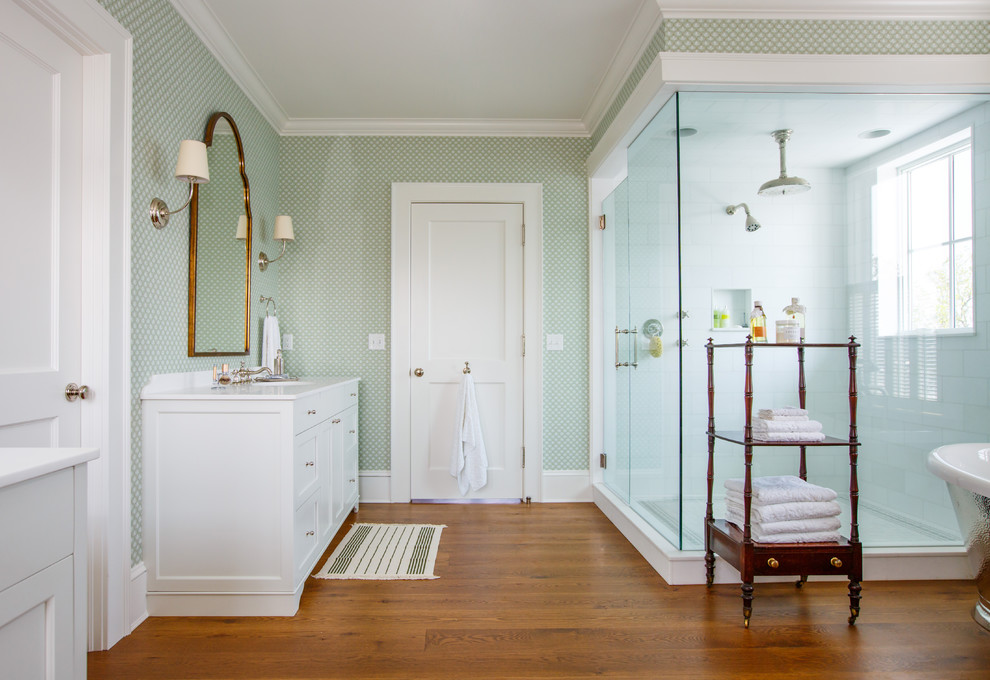 Inspiration for a traditional master bathroom in Jacksonville with shaker cabinets, white cabinets, a corner shower, white tile, multi-coloured walls, medium hardwood floors, a hinged shower door and white benchtops.