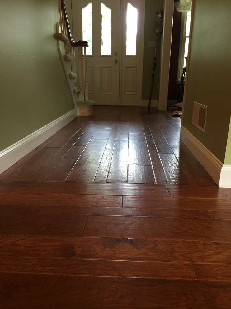 Front door - small rustic medium tone wood floor and brown floor front door idea with green walls and a white front door