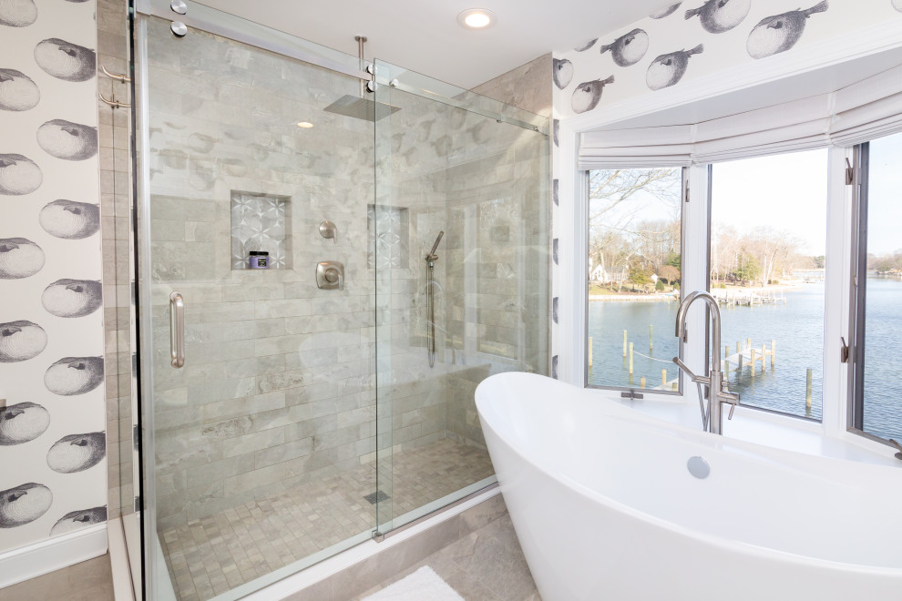 This is an example of a mid-sized beach style master bathroom in Baltimore with shaker cabinets, white cabinets, a freestanding tub, a double shower, a two-piece toilet, gray tile, subway tile, white walls, ceramic floors, an undermount sink, quartzite benchtops, grey floor, a sliding shower screen, multi-coloured benchtops, a niche, a double vanity, a freestanding vanity, timber and wallpaper.