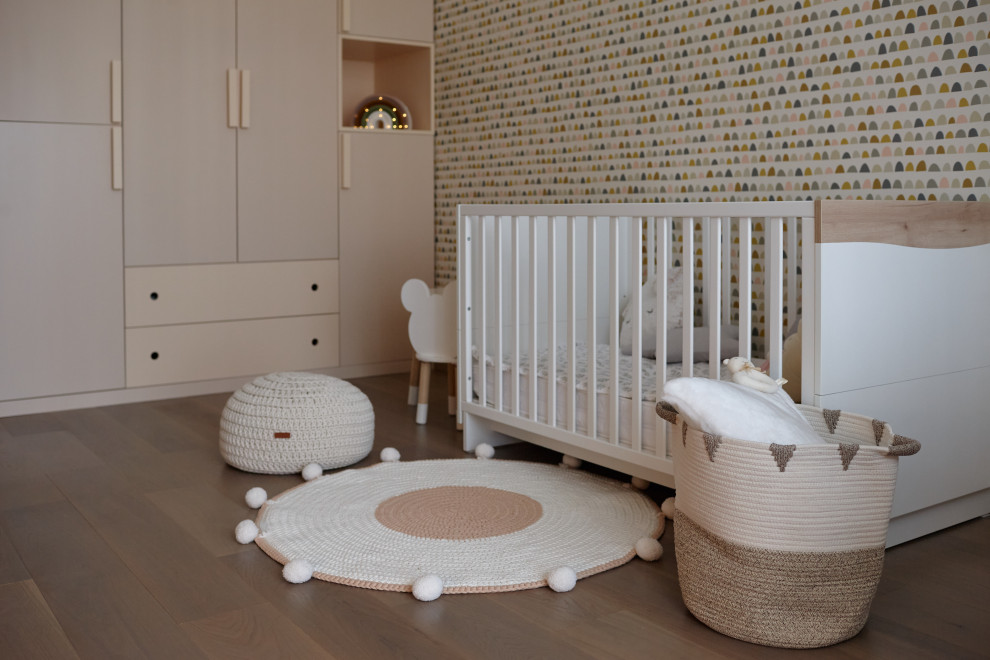 Imagen de habitación de bebé niña contemporánea de tamaño medio con paredes multicolor, suelo de madera en tonos medios, suelo beige y papel pintado