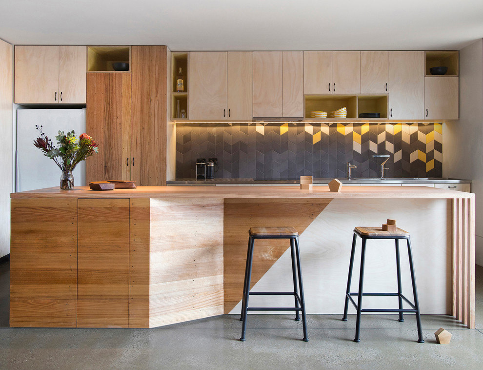 Design ideas for a mid-sized contemporary galley kitchen in Melbourne with flat-panel cabinets, light wood cabinets, multi-coloured splashback, white appliances, concrete floors and with island.