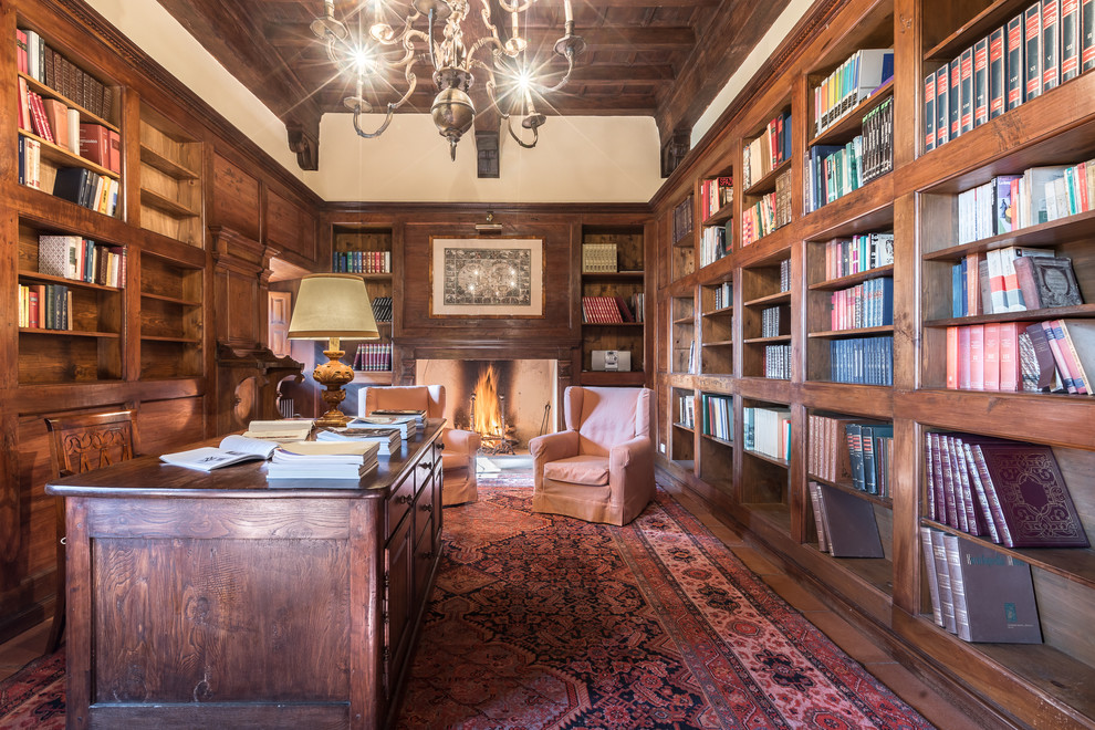 Inspiration for a large traditional home office in Florence with a library, white walls, a standard fireplace, a wood fireplace surround, a freestanding desk, dark hardwood floors and brown floor.