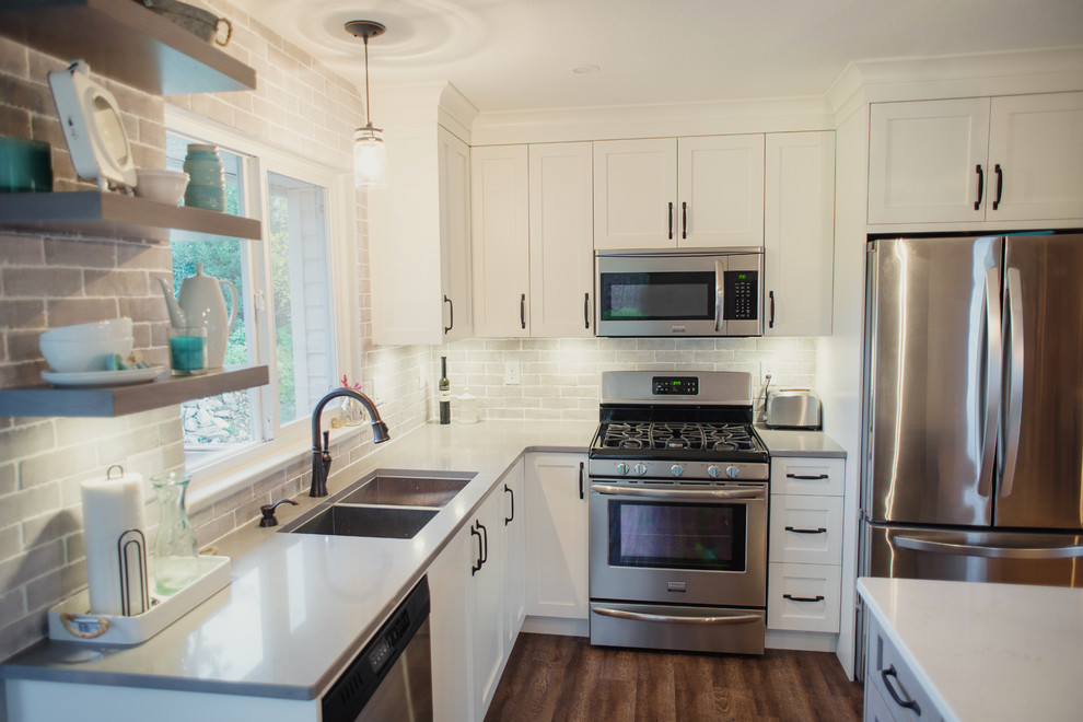 Inspiration for a mid-sized transitional l-shaped eat-in kitchen remodel in Vancouver with an undermount sink, shaker cabinets, white cabinets, quartz countertops, gray backsplash, stainless steel appliances, an island, porcelain backsplash and white countertops