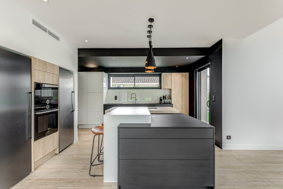 Inspiration for a large contemporary u-shaped open plan kitchen in Toulouse with a double-bowl sink, beaded inset cabinets, light wood cabinets, white splashback, glass sheet splashback, stainless steel appliances, with island, black benchtop, ceramic floors and beige floor.