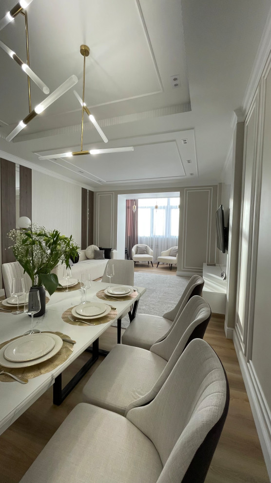 Modern inredning av ett stort vardagsrum, med beige väggar, laminatgolv och en väggmonterad TV
