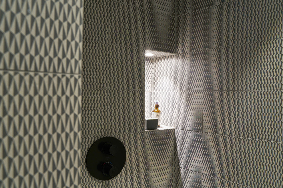 Geometrisch gemusterte Wandfliesen in der Dusche mit beleuchteter Nische