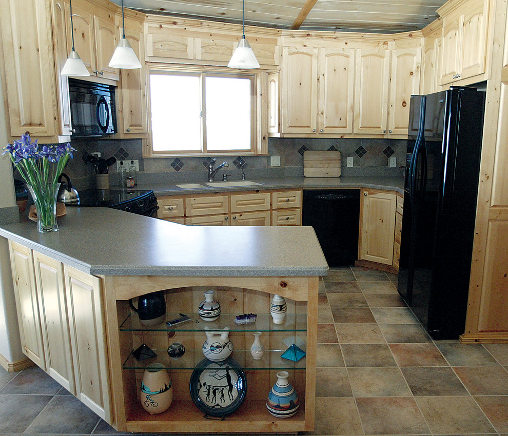 Kitchen - small rustic porcelain tile kitchen idea in Denver with an undermount sink, raised-panel cabinets, light wood cabinets, solid surface countertops and black appliances