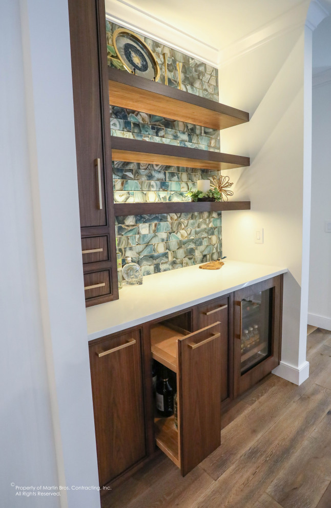 Small transitional single-wall home bar in Other with flat-panel cabinets, medium wood cabinets, quartzite benchtops, blue splashback, glass sheet splashback, medium hardwood floors and white benchtop.