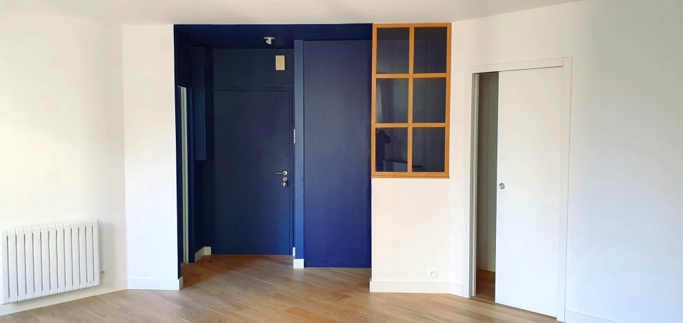 Idée de décoration pour une petite entrée minimaliste avec un mur bleu, parquet clair, une porte simple, une porte bleue et un sol beige.
