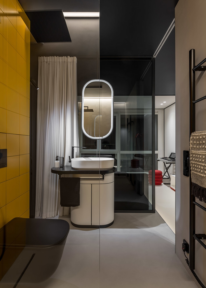 Photo of a mid-sized contemporary 3/4 bathroom in Other with furniture-like cabinets, white cabinets, a curbless shower, a wall-mount toilet, yellow tile, ceramic tile, black walls, a pedestal sink, grey floor, an open shower and black benchtops.