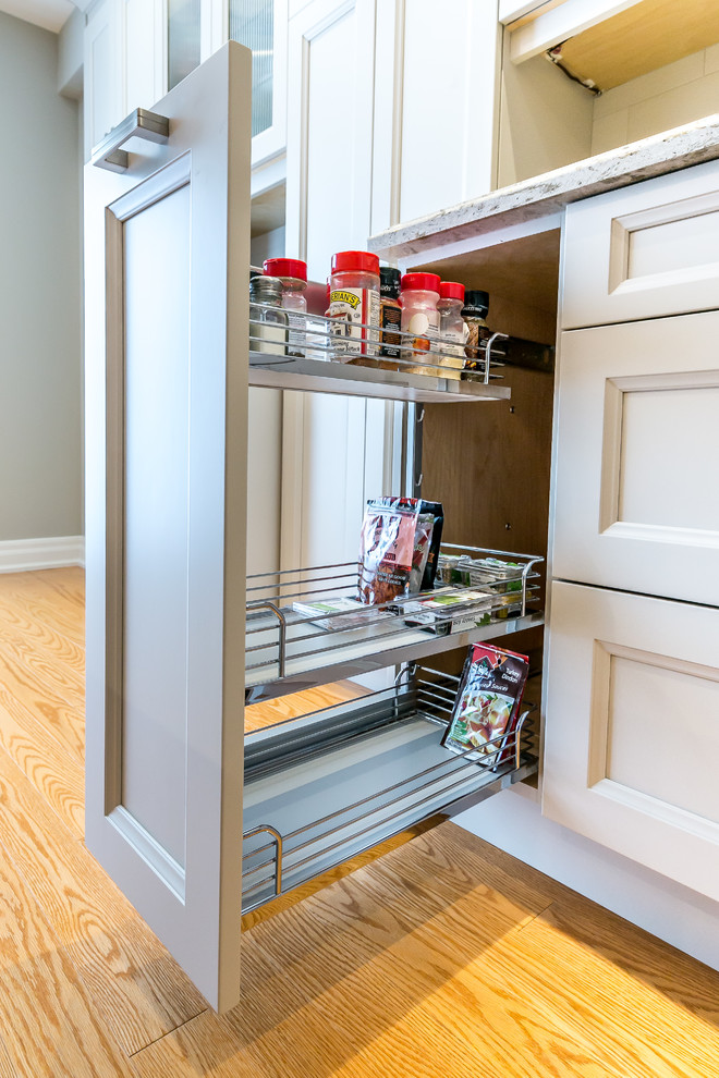 Example of a mid-sized transitional l-shaped brown floor kitchen design in Toronto with a double-bowl sink, white cabinets, white backsplash, stainless steel appliances and an island