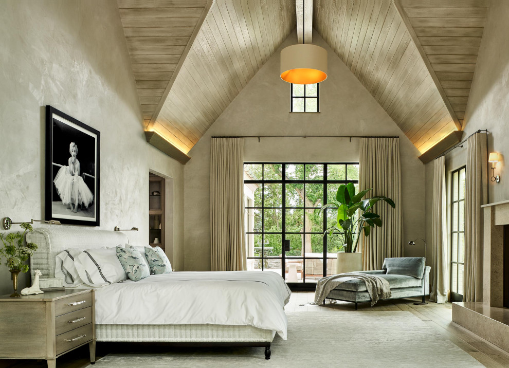Cette image montre une grande chambre parentale traditionnelle avec un mur beige, un sol en bois brun, une cheminée standard, un manteau de cheminée en pierre, un sol marron et un plafond voûté.