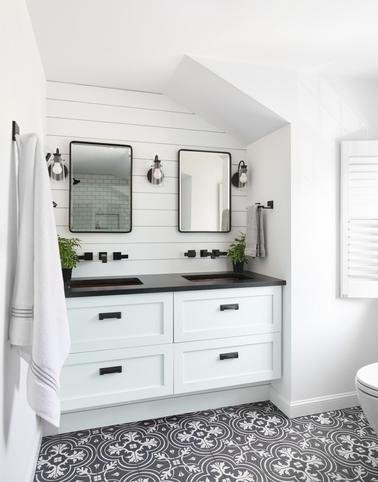 Photo of a beach style bathroom in Boston with shaker cabinets, white cabinets, white walls, an undermount sink, black floor, black benchtops, a double vanity, planked wall panelling and a built-in vanity.