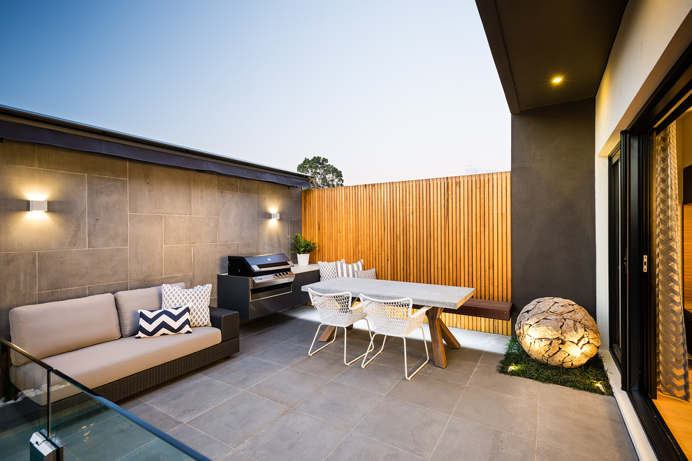 Inspiration for a small contemporary backyard patio in Melbourne with natural stone pavers and an awning.