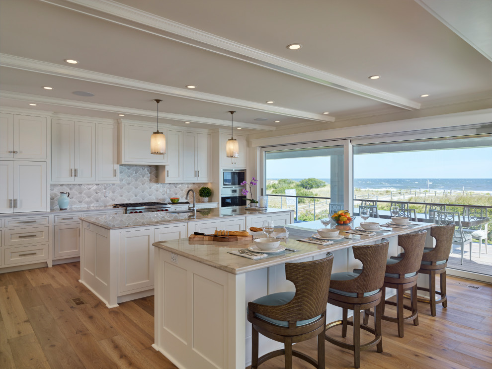 This is an example of an expansive transitional galley eat-in kitchen in Other with recessed-panel cabinets, white cabinets, marble benchtops, grey splashback, stainless steel appliances, medium hardwood floors, multiple islands, grey benchtop, coffered, an undermount sink and beige floor.