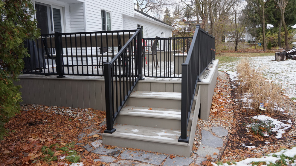 Design ideas for a mid-sized backyard and ground level deck in Detroit with with skirting, no cover and metal railing.
