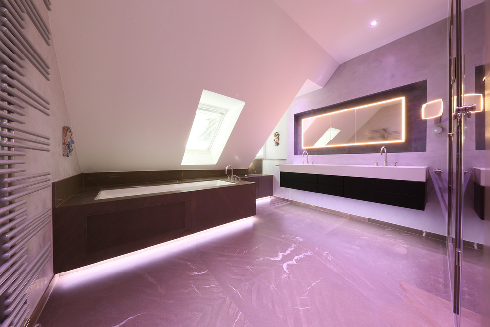 Geräumiges Modernes Badezimmer mit Whirlpool, Duschnische, Wandtoilette, grauen Fliesen, Marmorfliesen, grauer Wandfarbe, Marmorboden, Einbauwaschbecken, Mineralwerkstoff-Waschtisch, grauem Boden, Falttür-Duschabtrennung und weißer Waschtischplatte in München