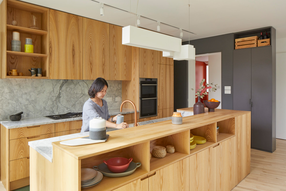 Contemporary open plan kitchen in London with light wood cabinets and an island.