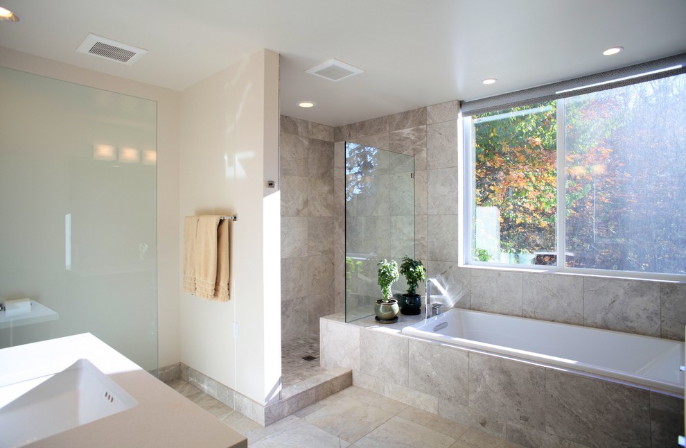 This is an example of a large contemporary master bathroom in Seattle with an undermount sink, flat-panel cabinets, dark wood cabinets, engineered quartz benchtops, a drop-in tub, an open shower, a two-piece toilet, gray tile, stone tile, white walls, limestone floors, brown floor and an open shower.