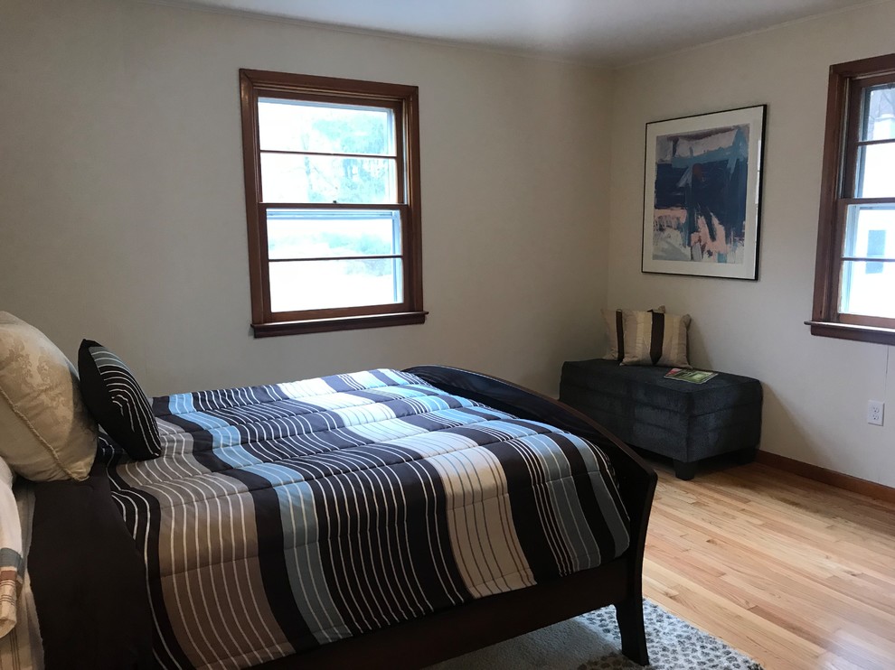 Photo of a mid-sized transitional guest bedroom in New York with white walls, medium hardwood floors, no fireplace and brown floor.