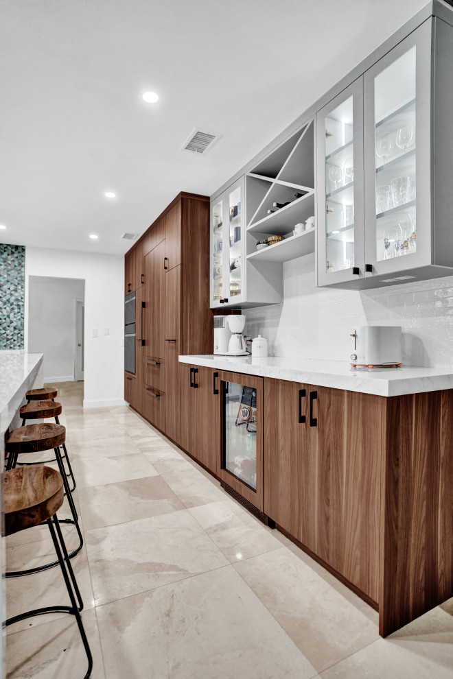 Cette photo montre une cuisine américaine moderne en bois brun avec un placard à porte plane, une crédence bleue, îlot et un plan de travail blanc.