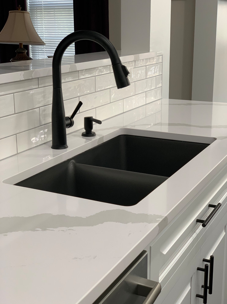 Example of a transitional marble floor and black floor eat-in kitchen design with an undermount sink, quartz countertops, ceramic backsplash, stainless steel appliances, an island and white countertops
