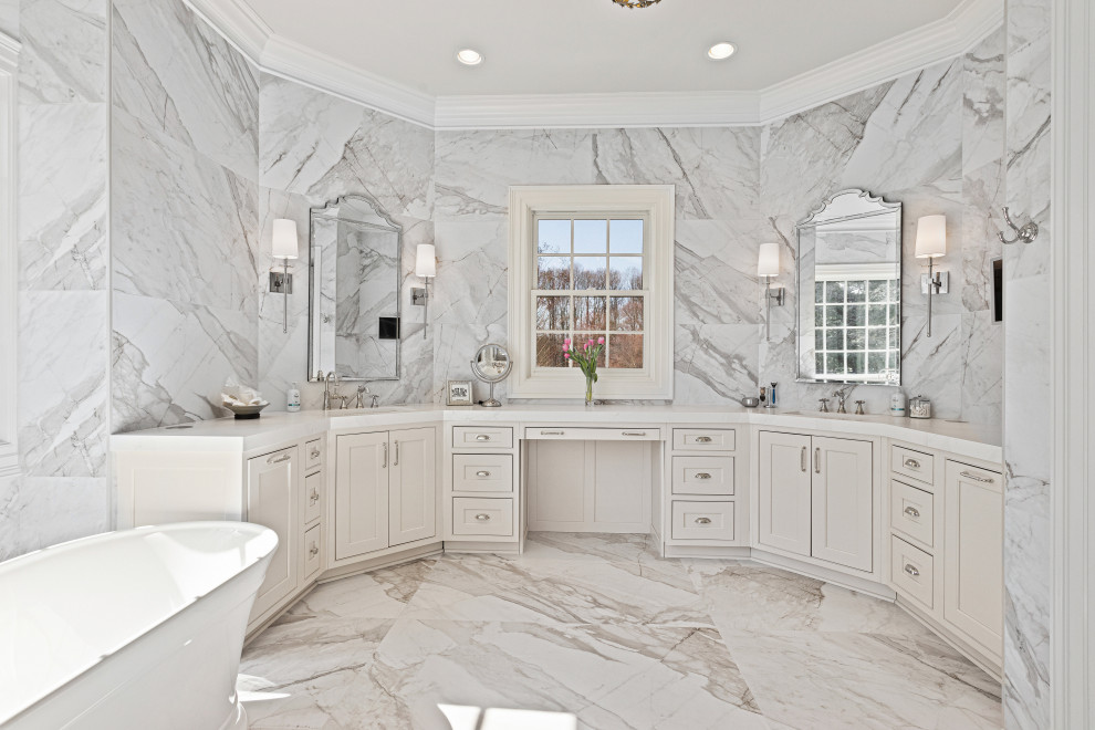 Foto di una stanza da bagno chic con ante a filo, ante bianche, vasca freestanding, piastrelle di marmo, top in quarzo composito e porta doccia a battente