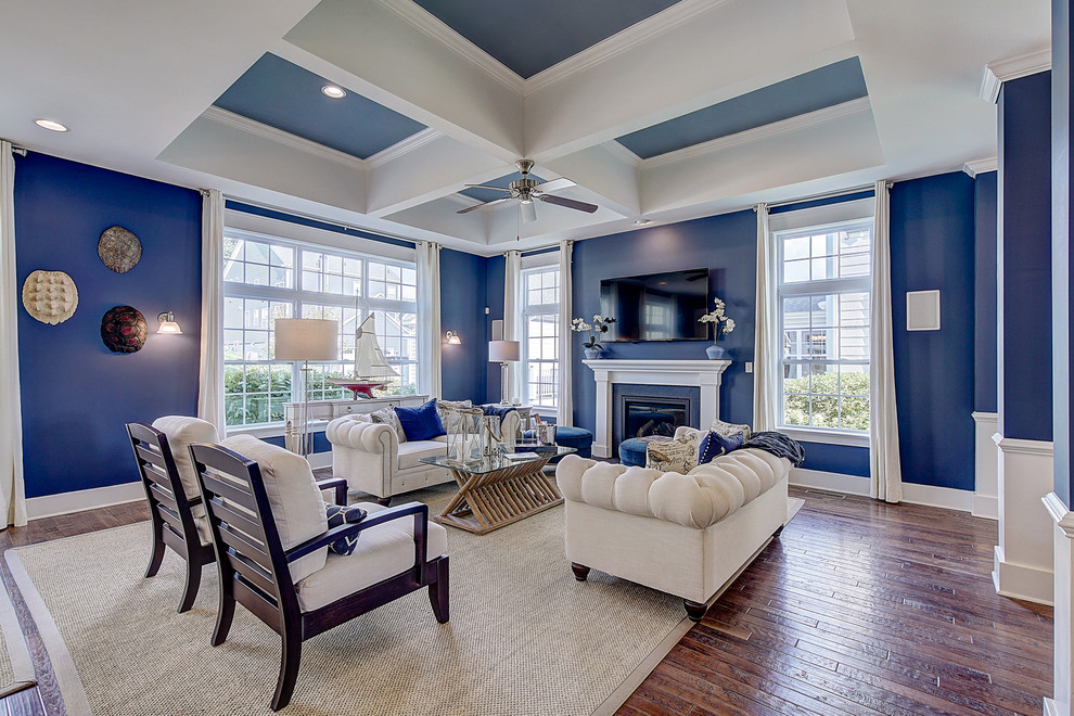 Mid-sized traditional open concept living room in Philadelphia with blue walls, medium hardwood floors, a standard fireplace, a wood fireplace surround, a wall-mounted tv, brown floor, coffered and decorative wall panelling.