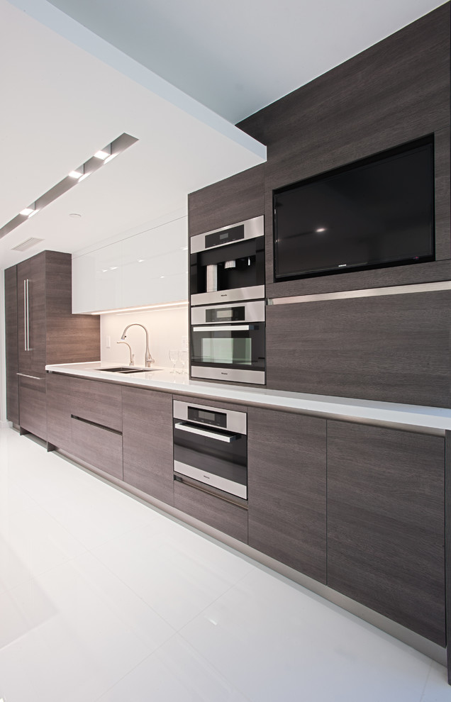 This is an example of a large modern u-shaped eat-in kitchen in Miami with a double-bowl sink, flat-panel cabinets, dark wood cabinets, solid surface benchtops, white splashback, stone slab splashback, stainless steel appliances, ceramic floors and no island.