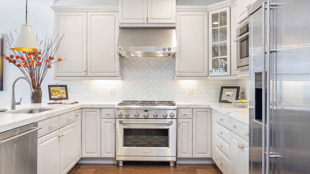 Inspiration for a mid-sized transitional u-shaped medium tone wood floor and brown floor eat-in kitchen remodel in Boston with an undermount sink, raised-panel cabinets, white cabinets, quartz countertops, white backsplash, subway tile backsplash, stainless steel appliances, a peninsula and white countertops