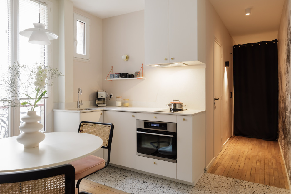 Design ideas for a small scandinavian l-shaped open plan kitchen in Paris with an undermount sink, beaded inset cabinets, white cabinets, quartzite benchtops, white splashback, engineered quartz splashback, black appliances, terrazzo floors, no island, multi-coloured floor and white benchtop.