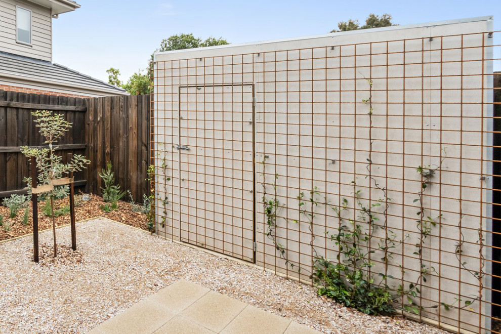 This is an example of a small and australian native industrial backyard full sun xeriscape for spring in Melbourne with a vertical garden and decomposed granite.