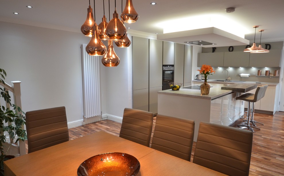 Mid-sized contemporary galley eat-in kitchen in Other with a drop-in sink, grey cabinets, grey splashback, black appliances, medium hardwood floors, with island, flat-panel cabinets, laminate benchtops, brick splashback and brown floor.
