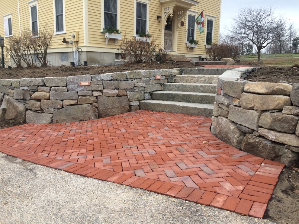 This is an example of a front yard garden in Manchester with a retaining wall and brick pavers.