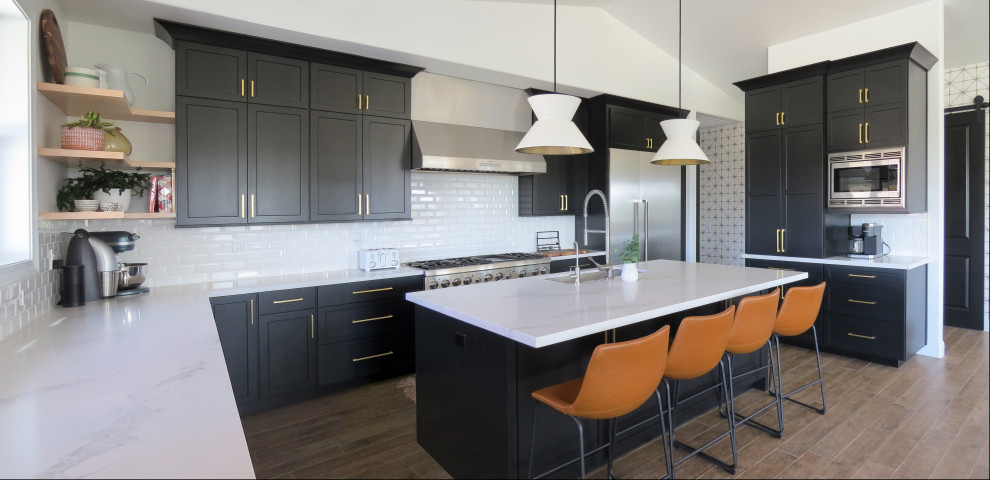 Large contemporary u-shaped open plan kitchen in San Luis Obispo with an undermount sink, shaker cabinets, black cabinets, marble benchtops, white splashback, subway tile splashback, stainless steel appliances, dark hardwood floors, with island, white benchtop and vaulted.